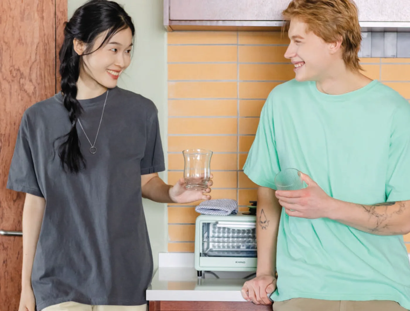 Two people in Comfort Colors 1717 garment-dyed tees in charcoal and island reef, chatting in a kitchen