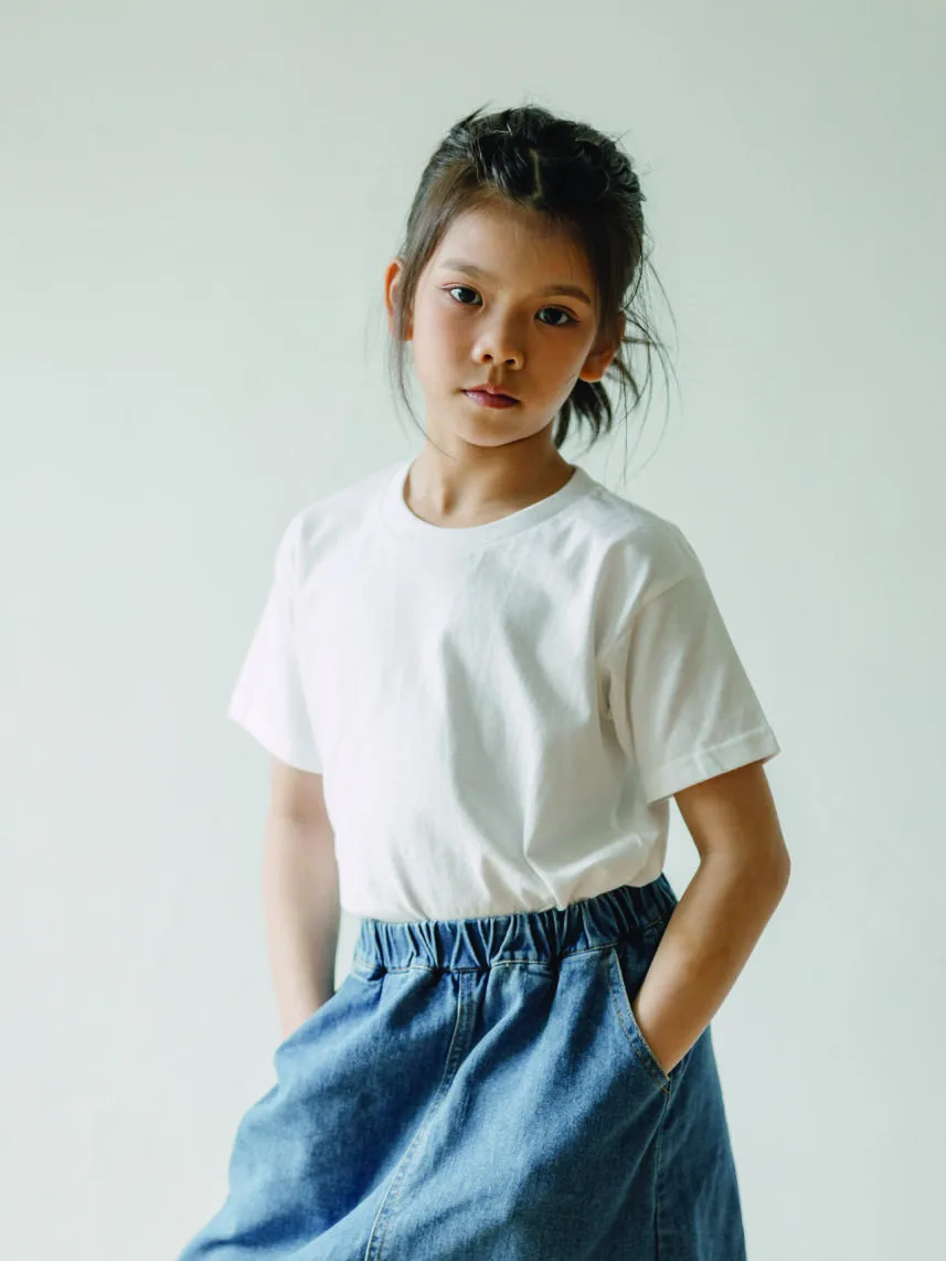 A girl wearing a white North Harbour NHR1100B youth tee with a denim skirt