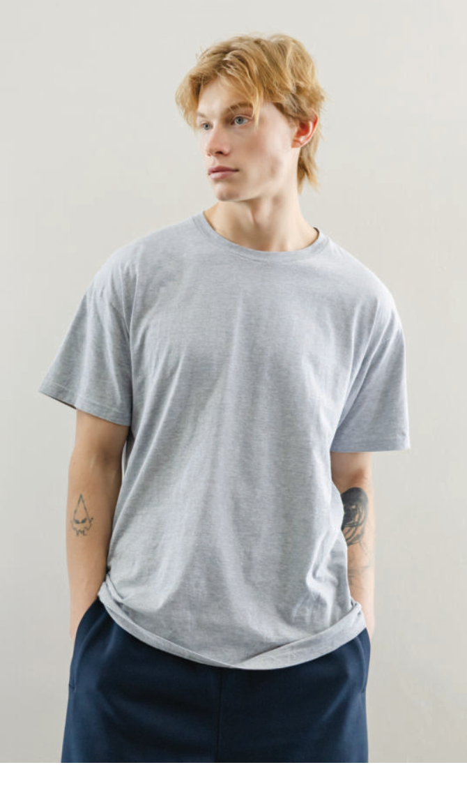 A person wearing a Gildan 63000 Softstyle round neck cotton t-shirt in heather grey
